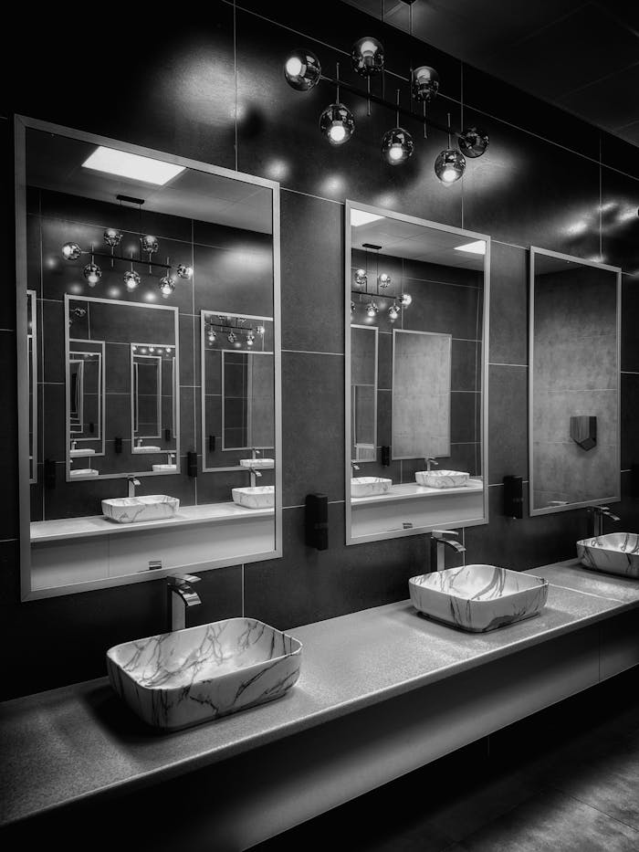 Black and white modern bathroom with stylish mirrors and lighting.